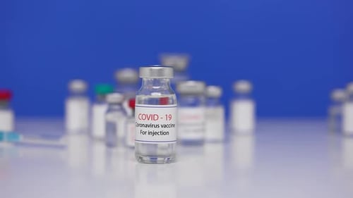 Flaschenimpfstoff gegen das SARS-CoV-2-Virus auf Hintergrundlabortabelle