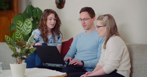 Group of Friends Using Laptop Together on Couch