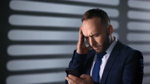 Worried Man Holding Phone in Office Environment