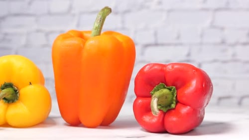 Yellow Orange and Red Capsicum on Table