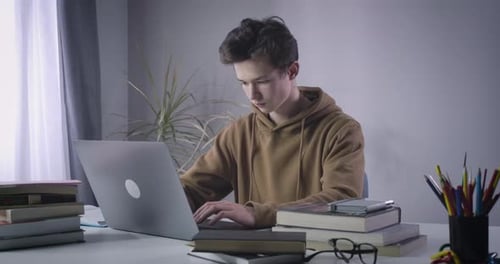 Unhappy Caucasian Boy Leaning Back From Laptop and Taking Head in Hands. Portrait of Stressed
