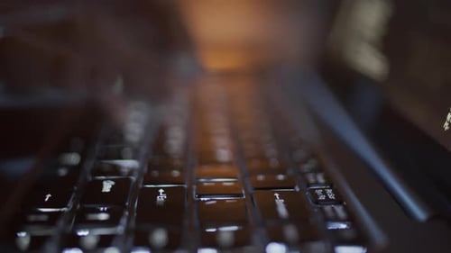 Hände einer anonymen Frau, die nachts Computercode auf Laptop schreibt