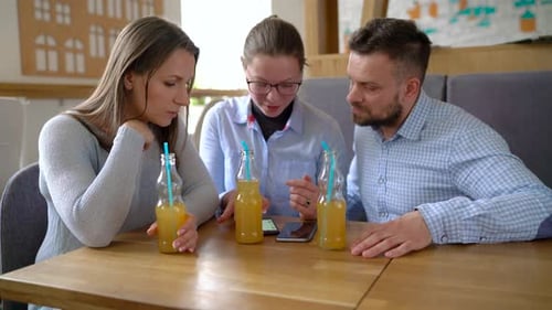 Three Friends Sit in a Cafe Drink Juice and Have Fun Communicating