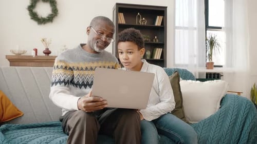 Grandfather and Grandson Using Laptop Together at Home