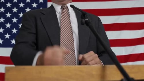 Speaker Gesturing Passionately at Podium with US Flag