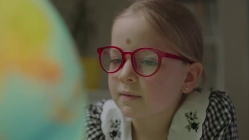 Close Up of Schoolgirl Studying Earth Globe at Home