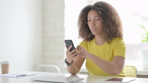 Woman Uses Mobile Phone at a Desk