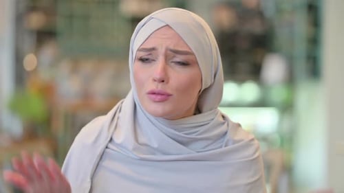 Frustrated woman in head covering arguing