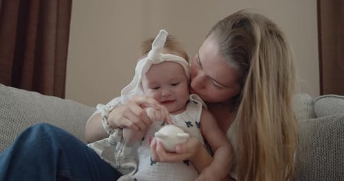 Loving Mother and Infant Play Together on Couch