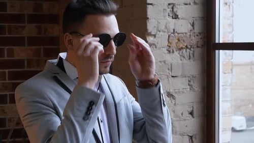 Man Puts on Stylish Sunglasses Indoors