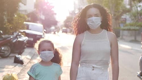 Mom and Daughter Are Standing on a Street in Protective Masks From the Covid-N1H1 Epidemic. Concept