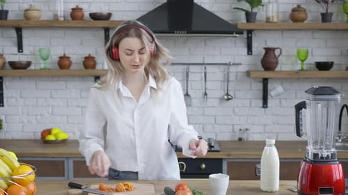 Woman Dances While Chopping Vegetables in Kitchen