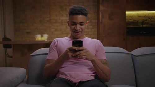 Excited Young Adult Using Mobile Phone on Couch