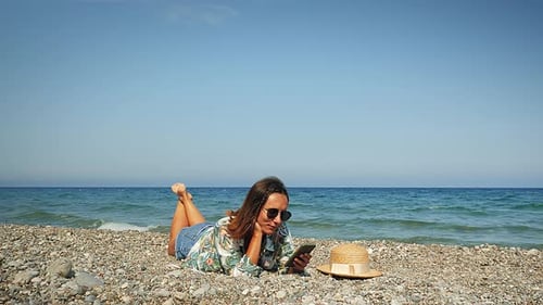 Woman on beach relaxing and sunbathing at windy sunny day.