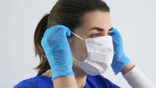 Woman Puts on Medical Face Mask and Gloves