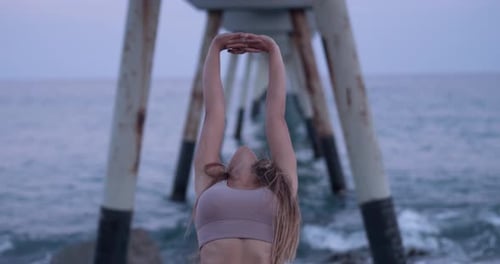 Young Woman Practicing Yoga and Stretching During a Sunset on the Beach