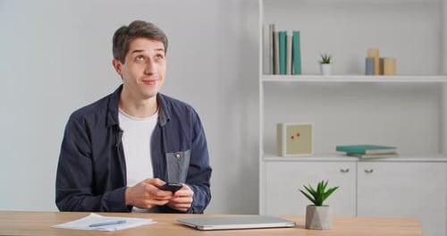 Young Man Using Phone at Desk Indoors