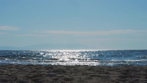 Calm sea, small waves slowly roll onto the sandy shore. Sea and sky background landscape.