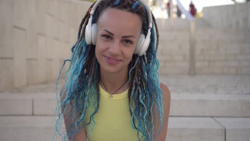 Porträt einer fröhlichen modernen jungen Frau mit Kopfhörern und Dreadlocks