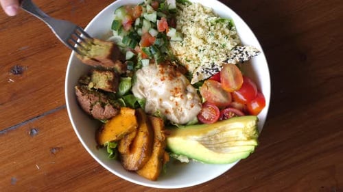 Top View of Fork Dipping a Falafel in Creamy Sauce and Showing in to the Camera