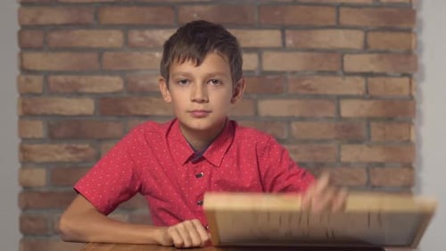 Kind sitzt am Schreibtisch mit Flipchart mit Schriftzug Jackpot auf dem Hintergrund Rote Backsteinmauer