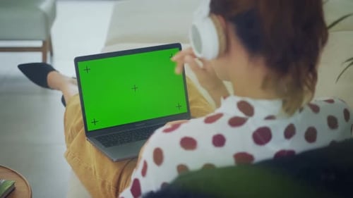 Vista posterior de una mujer de negocios trabajando en el interior de su casa en una computadora portátil