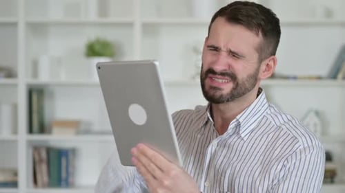 Distressed Man Holds a Tablet Device Indoors