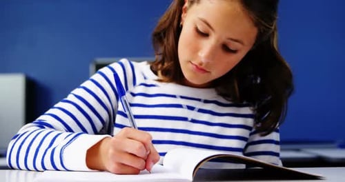 Girl Writing in Notebook in Classroom