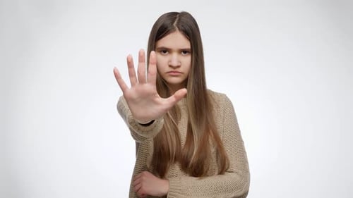 Portrait of Serious Girl Showing Stop or No Gesture with Hand Over White Studio Background