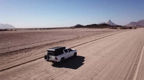 Conducción de automóviles en camino de grava en desierto aéreo