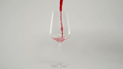 Red Wine Pouring into Glass on White Background