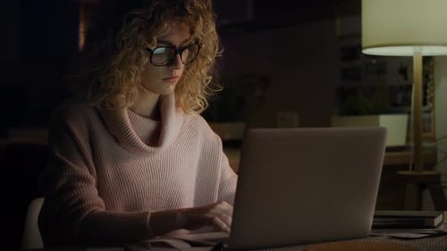 Woman Works on Laptop at Night, Removes Glasses