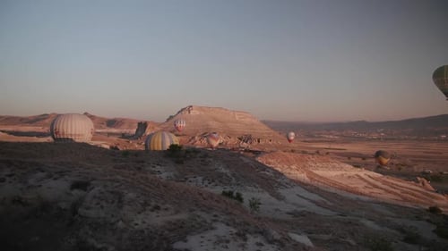 Hot Air Balloons Rising Over Desert Landscape at Sunrise