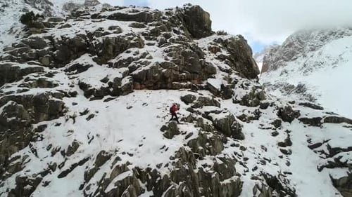 Climber Ascending Snow-Covered Mountain in Winter