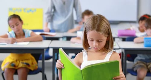 Smiling Girl Reads Book in Elementary Classroom
