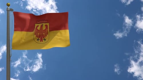 Red and Yellow Flag with Eagle Crest Waving in Blue Sky