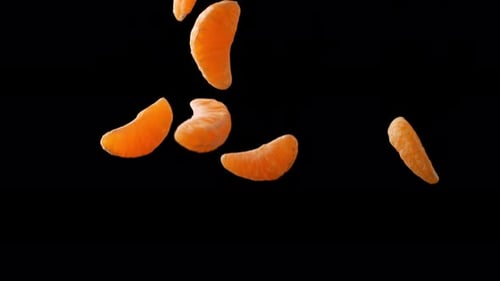 Orange slices falling on black background. Slow Motion.