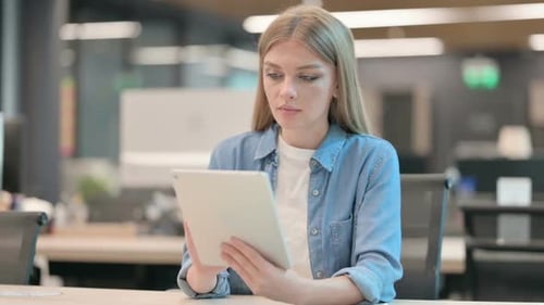 Young Woman Browsing Internet on Tablet in Office