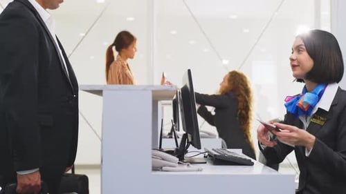 Smiling Airline Employee Checks Passport at Airport Counter