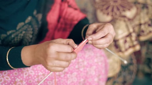 Close up of Indian woman's hands knits with craft needles and red wool. 4k Footage of knit work tie-