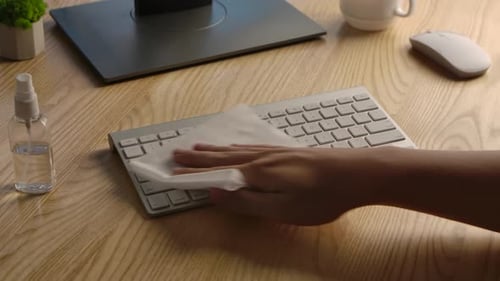 A Man Sprays Antiseptic on a Napkin and Disinfects a White Computer Keyboard and Then Types on It