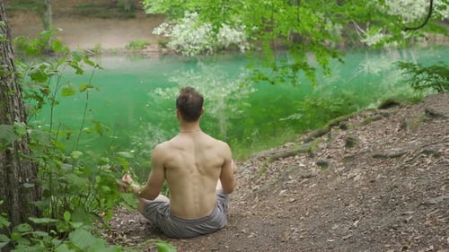 Young Adult Man Meditating by Lake