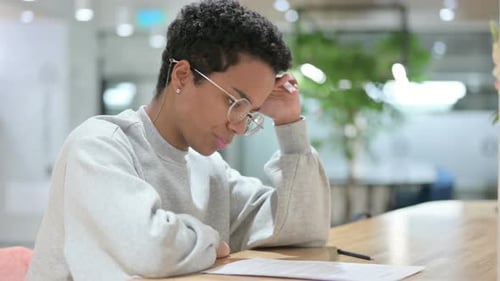 Woman Reads Documents at Desk Indoors