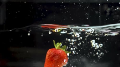 Eine reife Erdbeere, die in Zeitlupe in eine Flüssigkeit spritzt