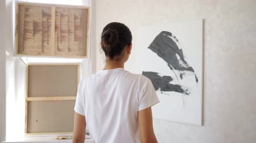 Young Woman Approaches Coloured Canvas and Draws Lines