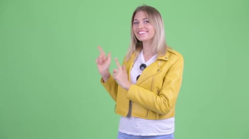 Glückliche junge rebellische blonde Frau zeigt mit dem Finger und zeigt etwas