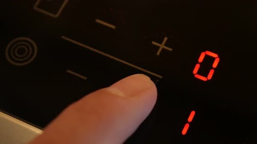 Finger Touches Stovetop Control Panel