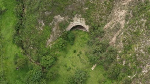 Aerial view approaching a large cave with a typical entrance