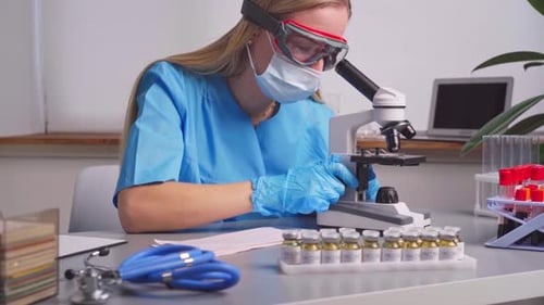 Woman Analyzing Sample with Microscope in Laboratory