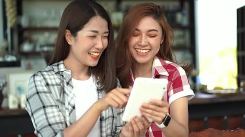 Women Friends Laughing While Using a Tablet Indoors